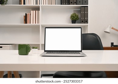 A laptop computer with empty display and office supplies on a desk in front of a bookshelf