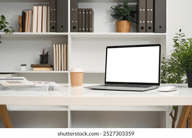 A laptop computer with empty display and office supplies on a desk in front of a bookshelf