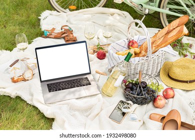 Laptop Computer And French Style Outdoor Picnic On The White Blanket. Wicker Basket With Baguettes, Wine, Fruits And Cheese Around. Pastel Green Bicycle In The Background. Summer Leisure - Lifestyle.