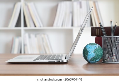 Laptop Computer And Globe On Desk In Library. Online Education, Lifelong Learning And Sharing Knowledge,