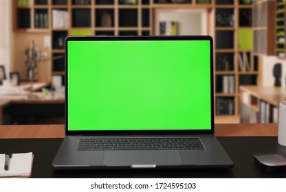 Laptop computer with Green screen Mock-up on working desk in office with no people