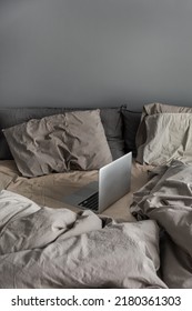 Laptop Computer In Grey Crumpled Bed With Linens, Pillows Against Grey Wall. Aesthetic Morning Composition. Freelancer, Outsourcing Minimalist Home Business, Work Concept.