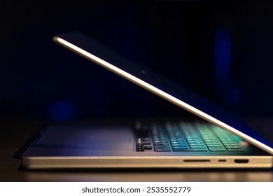 A laptop computer with a half-open screen on a dark background.