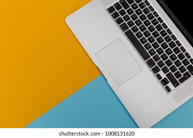 Laptop Computer Keyboard Overhead On Bright Yellow And Blue Background With Copy Space