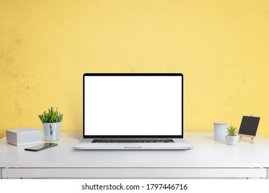 Laptop Computer Mockup On Office Desk With Yellow Wall In Background. Isolated Screen In White For Web Site Design Promotion