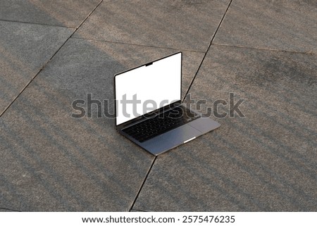 Laptop computer mockup template on a stone floor in an urban outdoor environment. Isolated surface to place your design. 