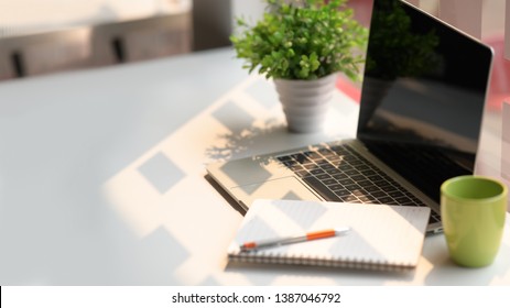 Laptop computer with notebook, coffee on white table in office workspace. - Shutterstock ID 1387046792