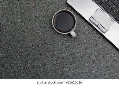 Laptop computer or notebook and a cup of coffee  on gray color modern working table or desk, work space with copy space top view.