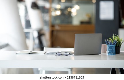 Laptop Computer, notebook, and eyeglasses sitting on a desk in a large open plan office space after working hours	
 - Powered by Shutterstock