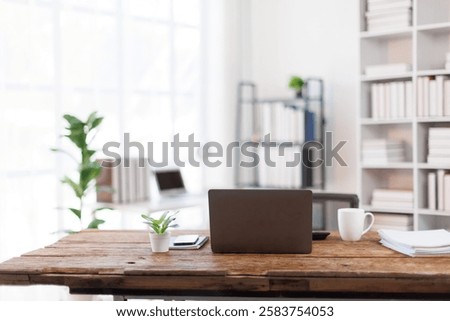 Laptop Computer, notebook, and eyeglasses sitting on a desk in a large open plan office space after working hours