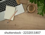 Laptop computer, notepad, coffee cup and houseplant on wooden table. Top view, flat lay with copy space