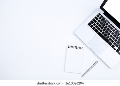 Laptop computer with notepad and pen on white background