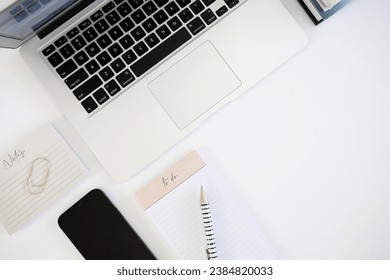 Laptop computer on desk with notes and phone