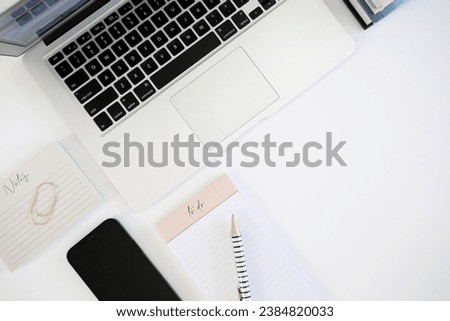 Laptop computer on desk with notes and phone