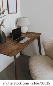 Laptop computer on table with lamp and comfortable chair. Aesthetic home office workspace interior design. Online shopping, online store, social media, blog branding