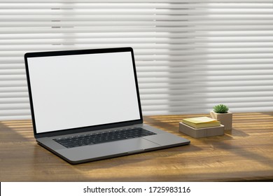 Laptop computer on a wooden surface with sticky notes and a desk plant 