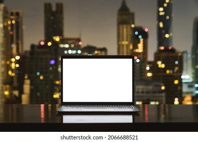 laptop computer on workspace white blank screen display city on night background