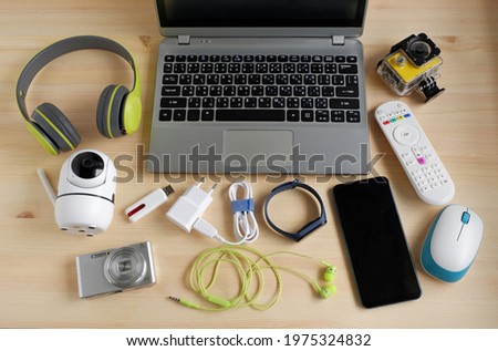 Laptop computer with smartphone and camera and other electronic gadgets on wooden background.Top view.