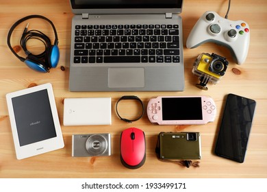 laptop computer with Smartphone and portable game consoles and ebook reader and many electronic gadgets on wooden background.Top view. - Shutterstock ID 1933499171