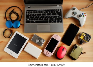 laptop computer with Smartphone and portable game consoles and ebook reader and many electronic gadgets on wooden background.Top view. - Shutterstock ID 1933499339