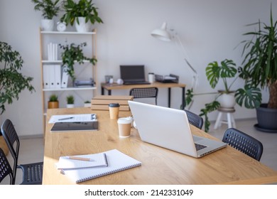 Laptop computer standing on wooden desk in workspace with different devices nearby. No people at the office. Stock photo  - Shutterstock ID 2142331049