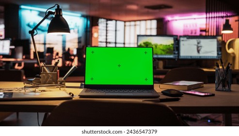 Laptop Computer Standing on a Wooden Desk with a Green Screen Chromakey Mock Up Display. Creative Office Working Station for Game Developer and Graphic Designer in Creative Agency - Powered by Shutterstock