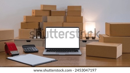 Laptop computer at workplace of start up, small business owner. cardboard parcel box of product for deliver to customer. Online selling, e-commerce, packing concept. laptop mockup screen view