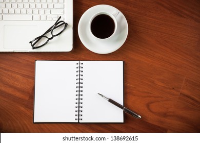 Laptop with cup of coffee and notepad on wooden background - Shutterstock ID 138692615