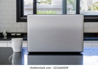 Laptop and cup of coffee on the kitchen island. Home office concept - Powered by Shutterstock