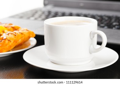 laptop and cup of hot evaporating coffee on table