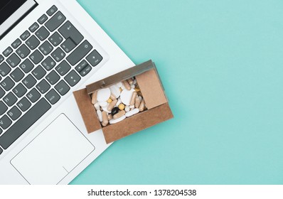 Laptop And Delivery Box Filled With Assorted Prescription Medicines: Drug Abuse And Online Pharmacy Shopping Concept