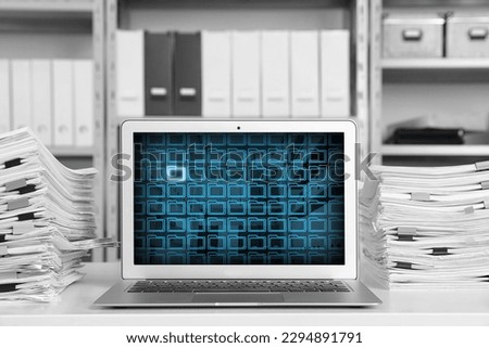 Laptop with digital archive program in office. Many folder icons and one highlighted on display