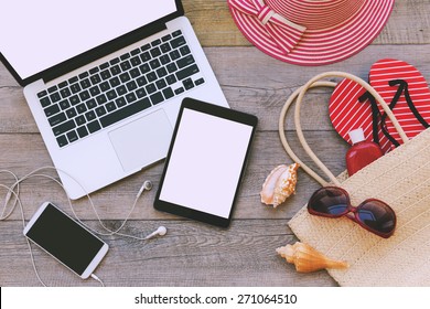 Laptop, digital tablet and smart phone with beach items over wooden background. View from above - Powered by Shutterstock