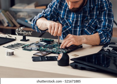 Laptop disassembling with screwdriver at repair shop. Engineer fixing broken computer motherboard. Electronic renovation, technology development concept
