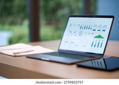 Laptop displaying data charts and analytics interface on a wooden desk in modern office setting