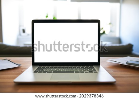 Laptop with empty blank screen on table at home