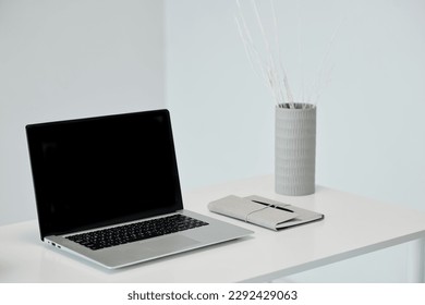 Laptop with empty screen and planner on office table