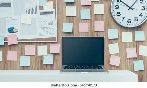 Laptop And Folders On A Shelf In The Office, Pinboard On The Background, Business Workspace And Technology