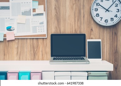 Laptop And Folders On A Shelf In The Office, Pinboard On The Background, Business Workspace And Technology