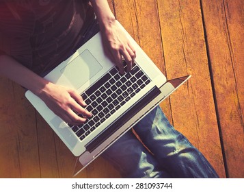 Laptop In Girls Hands Typing And Sitting On A Wooden Floor