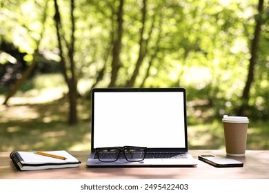 Laptop, glasses and smartphone on wooden table outdoors. Remote work - Powered by Shutterstock