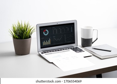 Laptop mit Graph-Diagramm Berichtsbildschirm auf dem Arbeitstisch. Heimbüro oder Arbeitsraum. Rechnungslegungskonzept für die Strategieanalyse