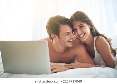 Laptop, happy and couple lying in bed together while watching a online movie or video at their home. Happiness, smile and portrait of a woman browsing the internet on computer with husband in bedroom - Powered by Shutterstock