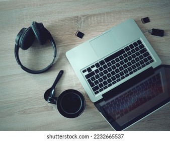 Laptop, headphone and a cup of coffee on a wooden table - Shutterstock ID 2232665537
