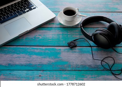 Laptop, Headphone, Music player, black coffee on blue wood table. With copy space. Business concept.