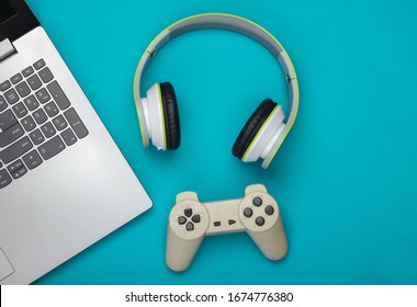 Laptop With Headphones, Gamepad On Blue Background. Gaming, Entertainment Or Leisure Concept. Top View. Flat Lay