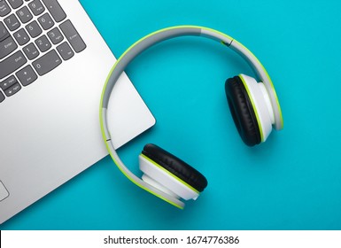 Laptop With Headphones On Blue Background. DJ, Gaming, Entertainment Or Leisure Concept. Top View. Flat Lay