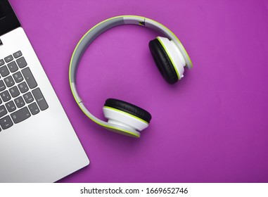 Laptop With Headphones On Purple Background. DJ, Gaming, Entertainment Or Leisure Concept. Top View. Flat Lay