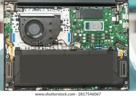 Laptop internal components are visible, featuring the motherboard, fan, and battery, highlighting the detailed electronic circuitry and layout