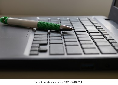 Laptop keyboard black on gray background with a pen on it. Close